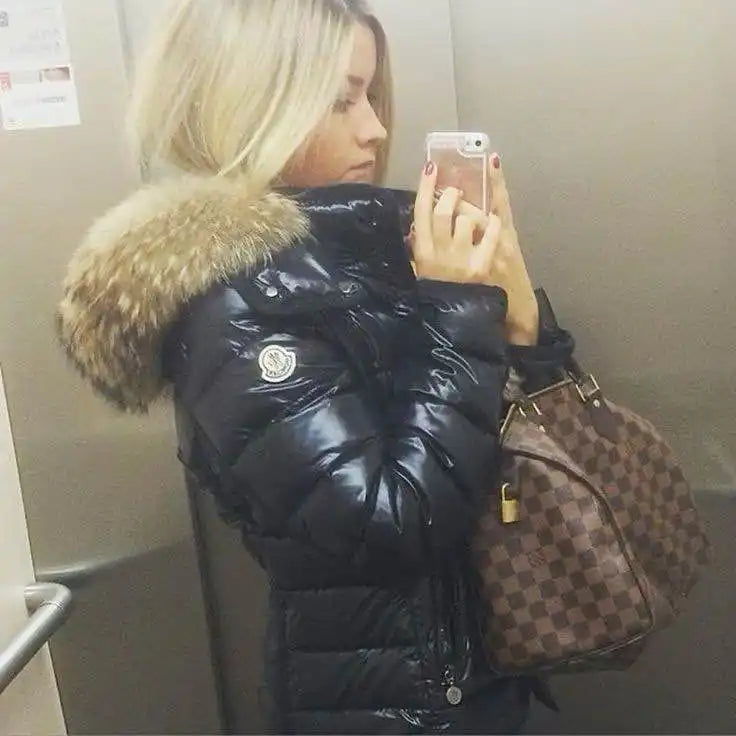 Manteau gonflant noir brillant avec capuche bordée de fourrure et un sac à main Louis Vuitton.