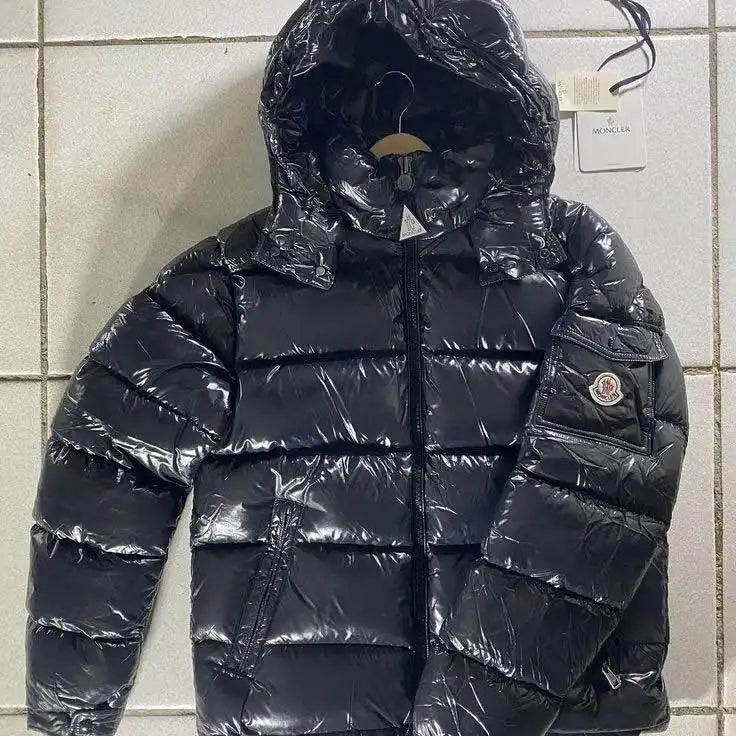 Doudoune noire brillante avec capuche et patch logo Moncler.