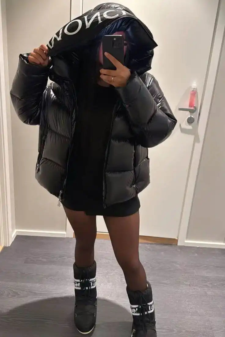 Veste d'hiver noire gonflante avec la marque 'MONCLER' portée avec des bottes et un short.