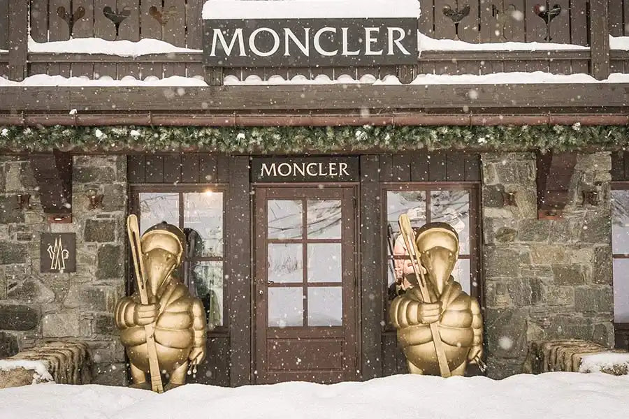 Une vitrine de magasin Moncler avec des statues de chevaliers dorées flanquant l'entrée.